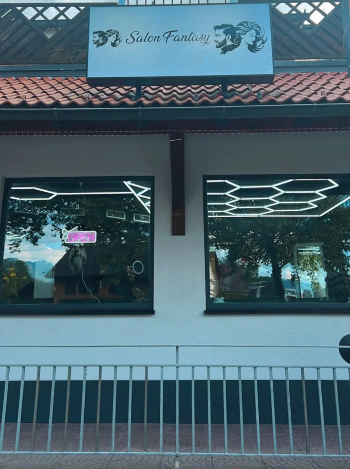 Ladenfront des Salon Fantasy mit beleuchtetem Schild über den Schaufenstern und rosa OPEN-Schriftzug